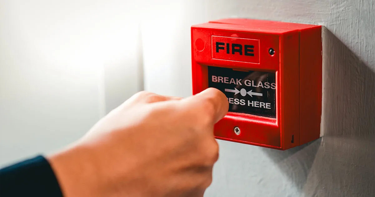 Hand reaching towards manual call point