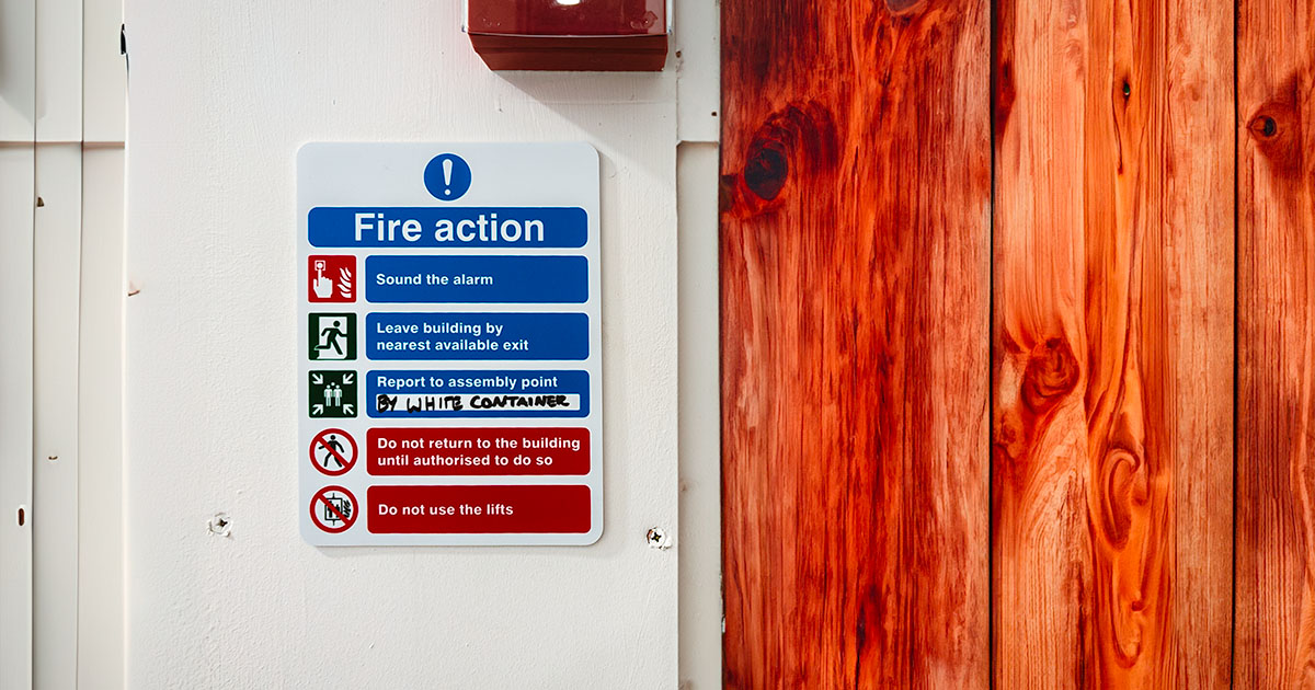 Fire action sign next to wooden wall