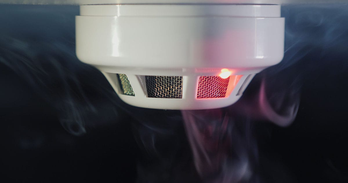 Smoke detector on ceiling with smoke surrounding it