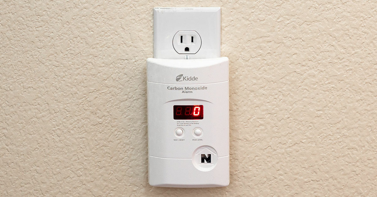 Carbon monoxide alarm plugged into textured cream wall