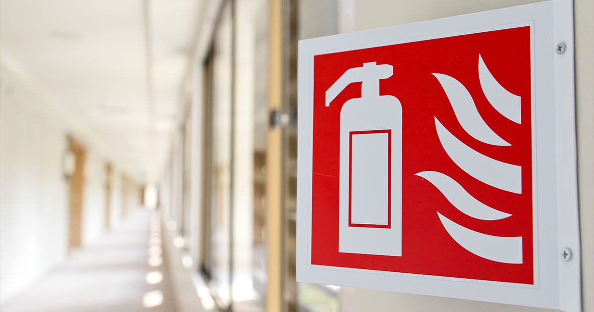 Angled fire extinguisher sign on wall in corridor