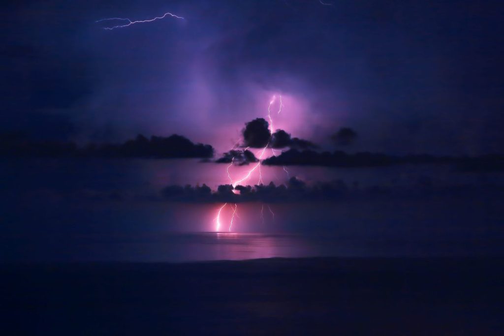 Purple lightning in sky over sea