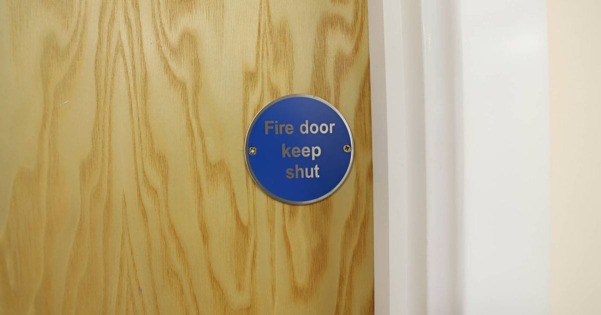 Fire door keep shut sign on wooden door