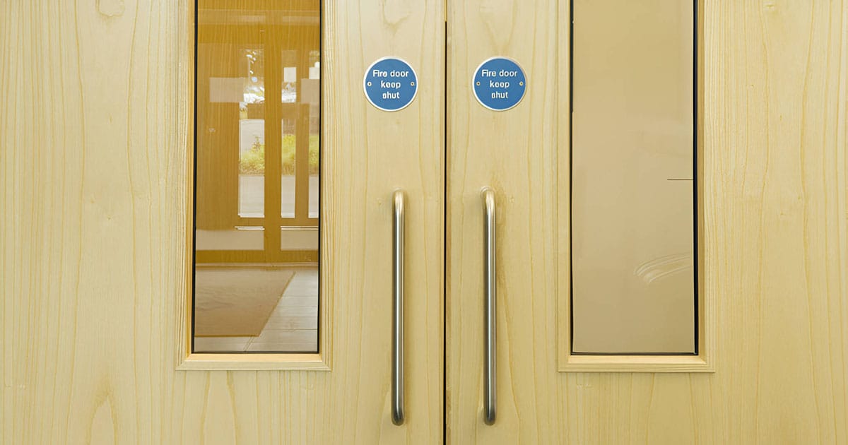 Fire door keep shut signs on wooden double door