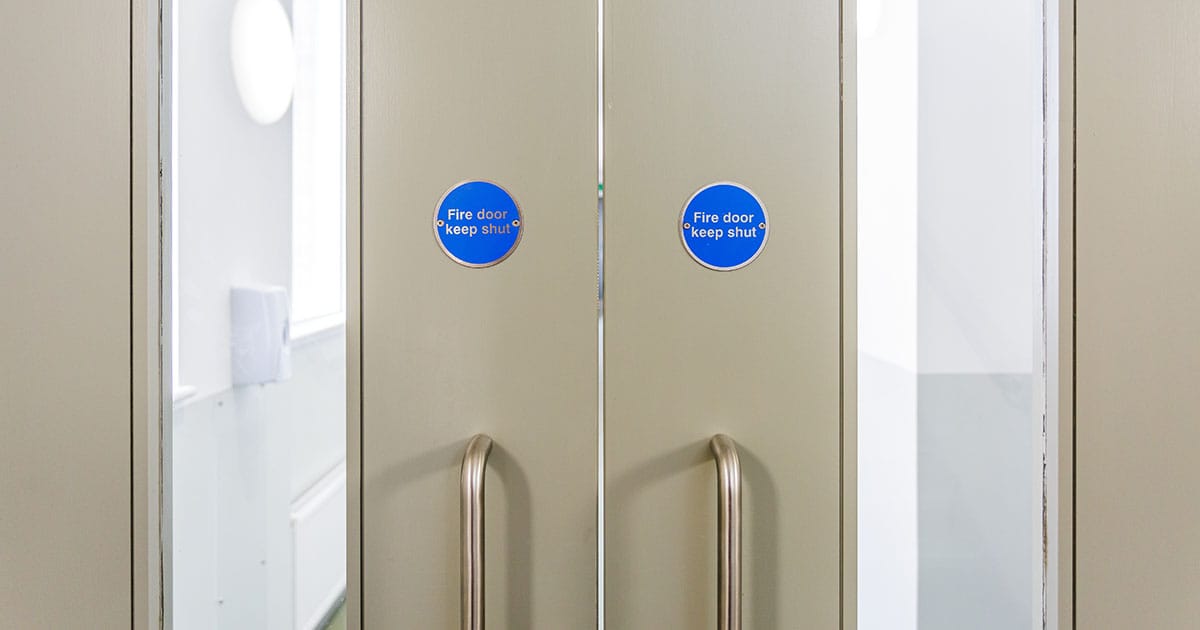 Fire door keep shut signs on white double door