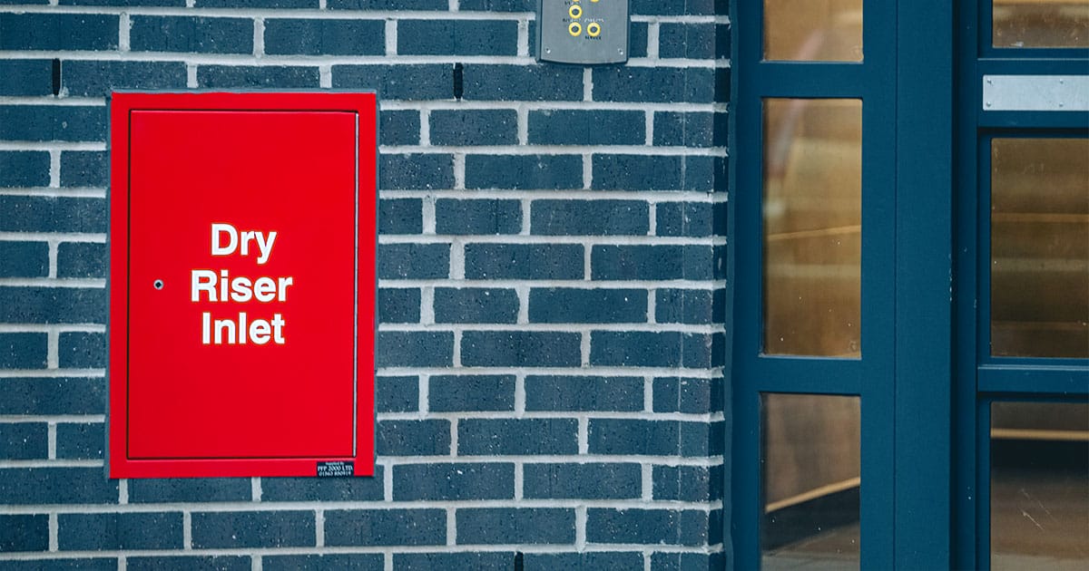 Dry riser inlet cabinet on dark blue brick wall