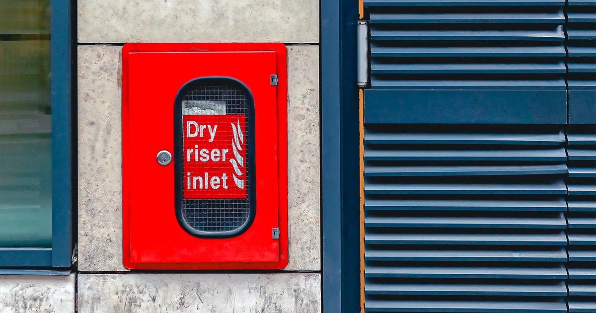 Dry Riser on wall with blue shutter Dry riser inlet cabinet on stone wall
